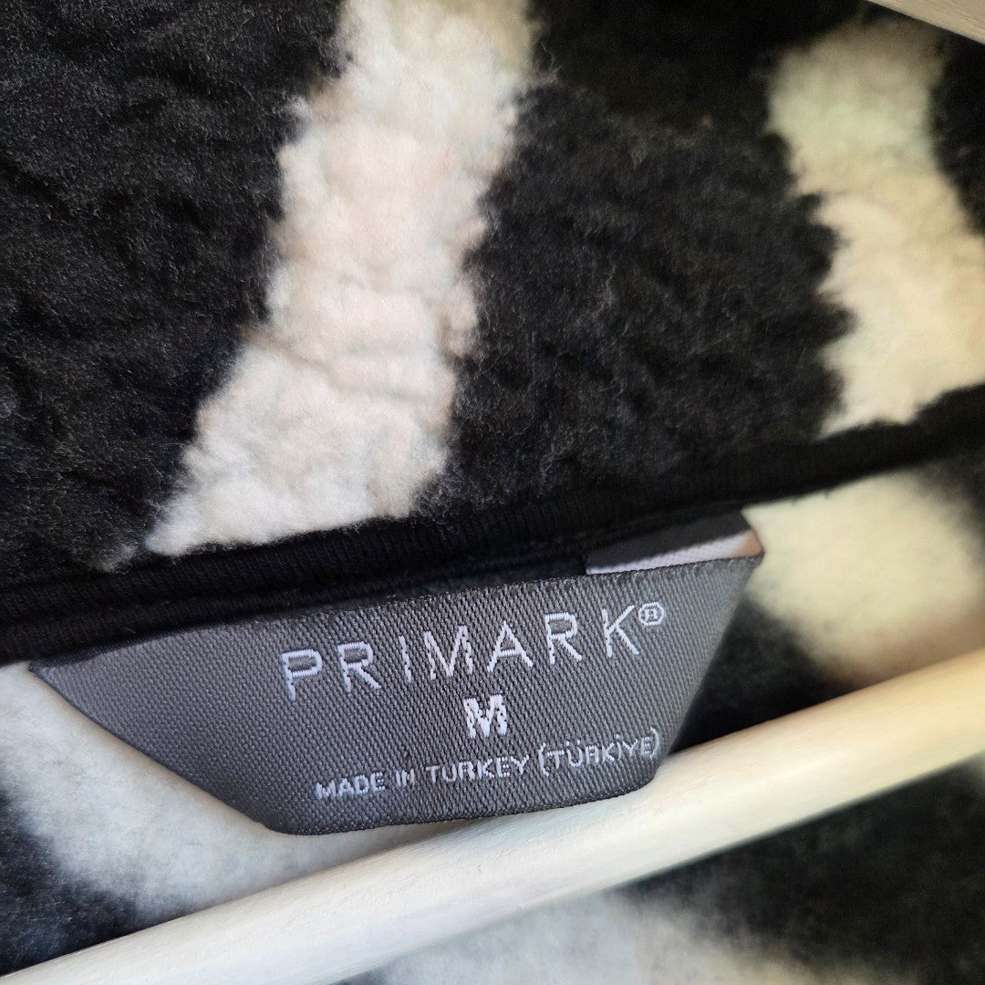 A close-up of a gray Primark tag on the Upcycled Breastfeeding & Pumping Zebra Zip Oversized Fleece M (100478), highlighting this comfy, affordable nursing option made in Turkey.