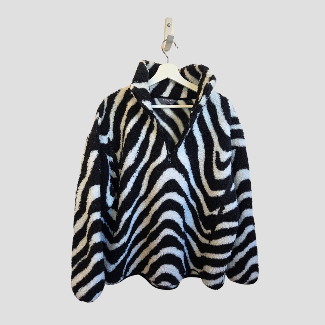 The Primark Upcycled Breastfeeding & Pumping Zebra Zip Oversized Fleece M (100478), featuring black-and-white zebra stripes, hangs on a white hanger against a plain light gray background—ideal for stylish and affordable nursing.