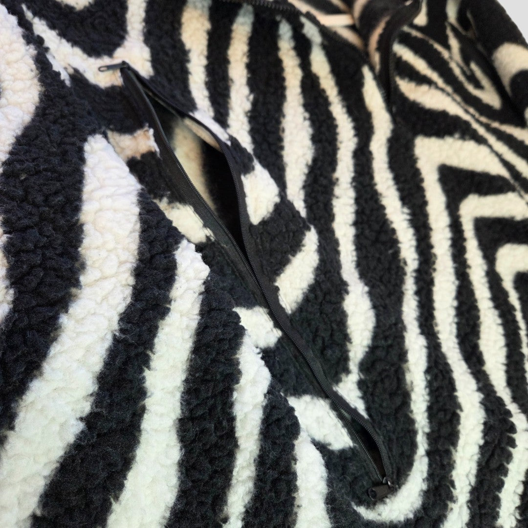 Close-up of Primark's Upcycled Breastfeeding & Pumping Zebra Zip Oversized Fleece (M, 100478) in black and white, featuring a soft textured fabric and an open zipper pocket for easy, affordable comfort and convenient nursing access.