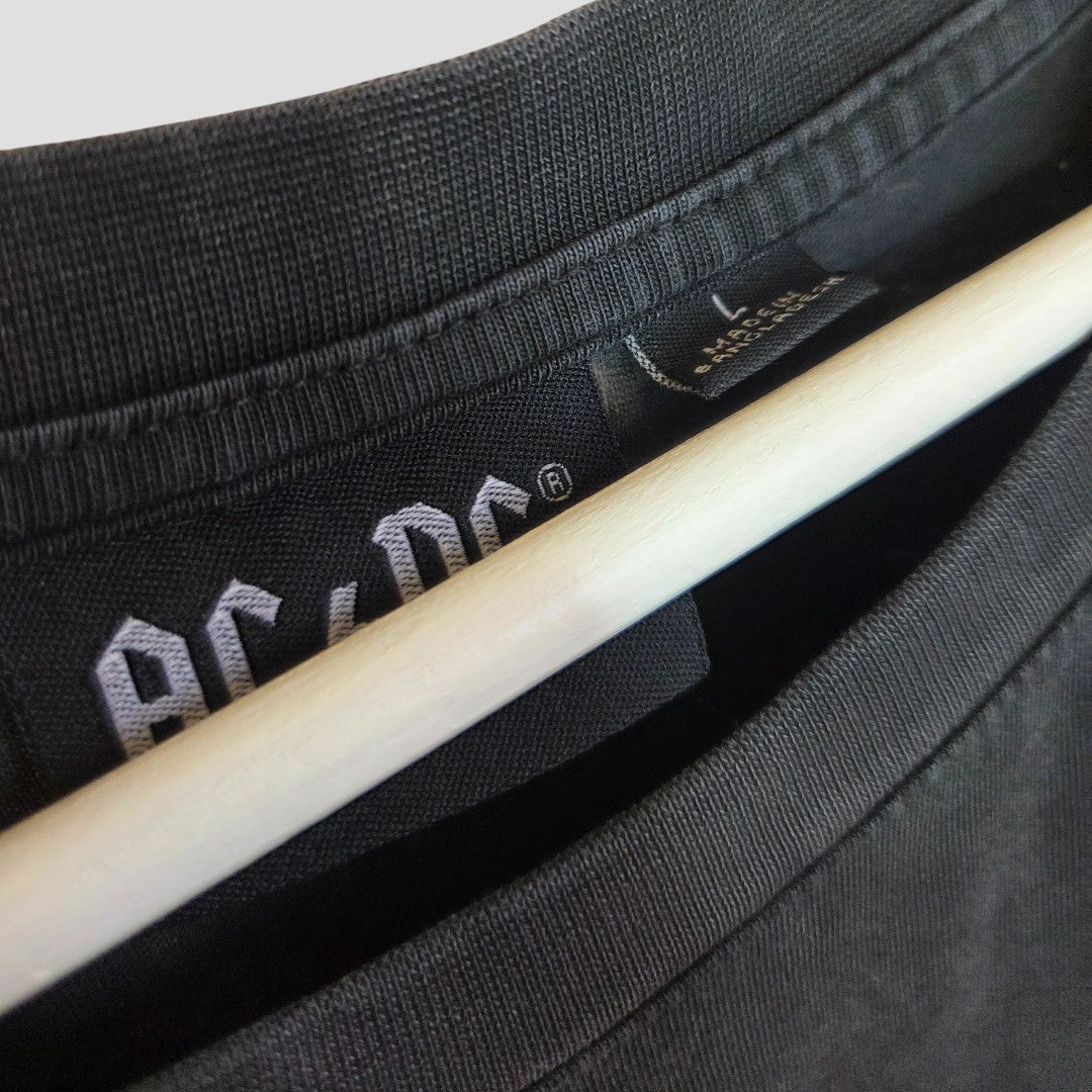 Close-up of a black Primark Upcycled Breastfeeding & Pumping AC/DC Faces Band t-shirt dress (L, UK14/16) on a wooden hanger, highlighting the neckline and visible white AC/DC lettering on the inner label.