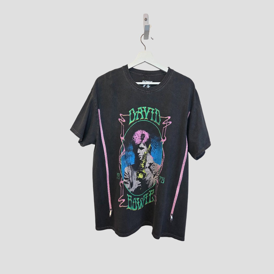 The Upcycled Breastfeeding & Pumping David Bowie Saxophone Band t-shirt (M/L, 100458) by David Bowie features a colorful saxophone graphic and green logo, made as an eco-friendly alternative. Shirt shown on white hanger against a plain background.