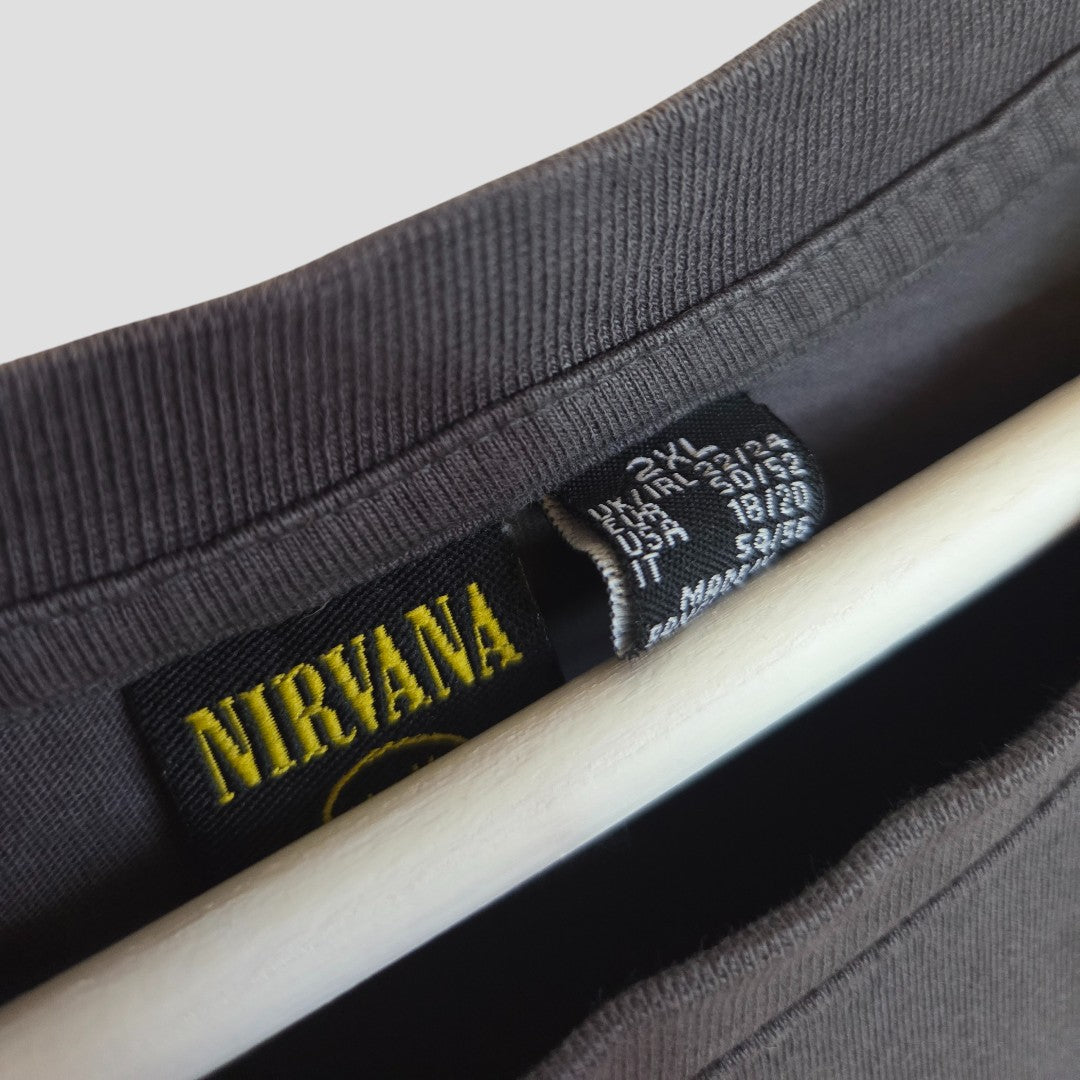 Close-up of a dark gray Primark Nirvana Smile Band t-shirt (2XL, UK22/24) on a hanger, showing the yellow Nirvana logo and black size tag—an upcycled, affordable breastfeeding & pumping clothing option.