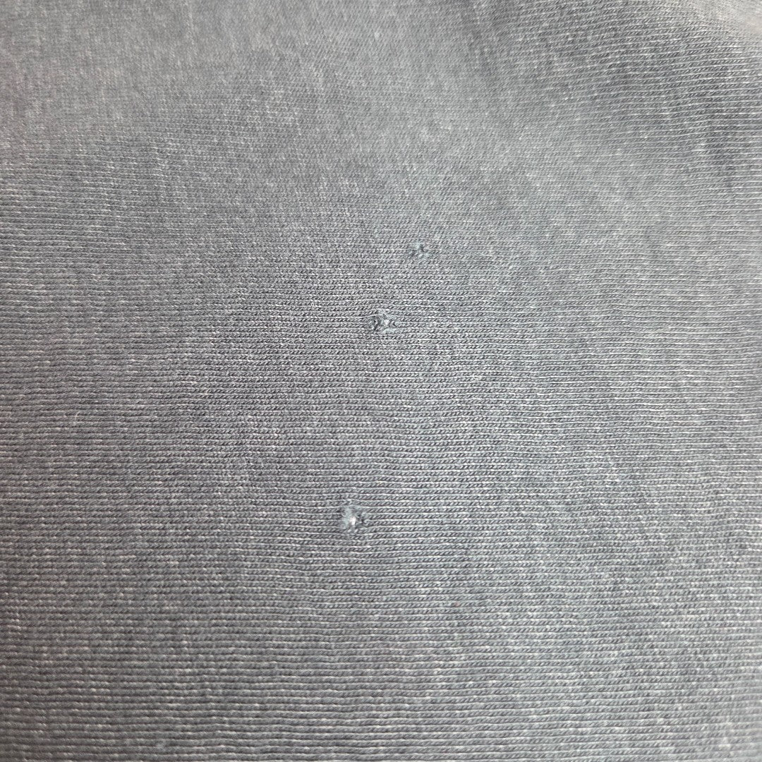 Close-up of gray fabric, like that in the Primark Upcycled Breastfeeding & Pumping AC/DC Faces Band t-shirt dress (UK14/16), with water droplets on top—emphasizing its textured surface and possible water-repellent qualities for nursing.