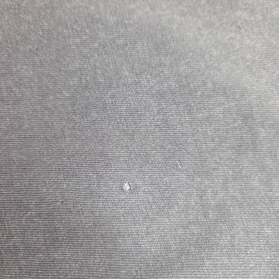 Close-up of gray fabric from Primark’s Upcycled Breastfeeding & Pumping AC/DC Faces Band t-shirt dress (L, UK14/16), showing a small snag and fine weave—ideal texture for comfortable nursing wear.