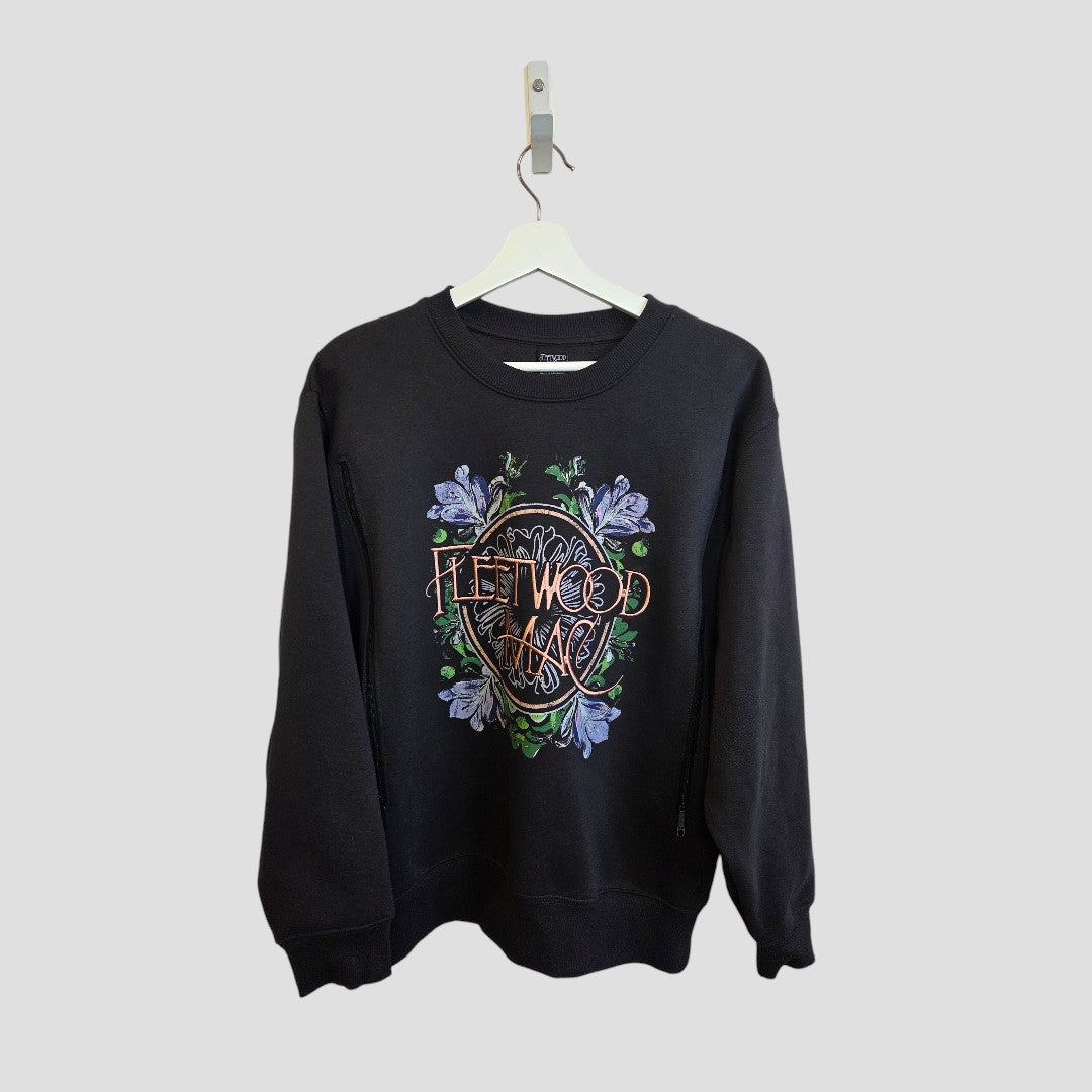 A black Primark crewneck sweatshirt (Upcycled Breastfeeding & Pumping Fleetwood Mac Band Sweatshirt S, 100433) with colorful graphics and floral embroidery, designed for nursing, hangs on a white hanger against a light gray background.