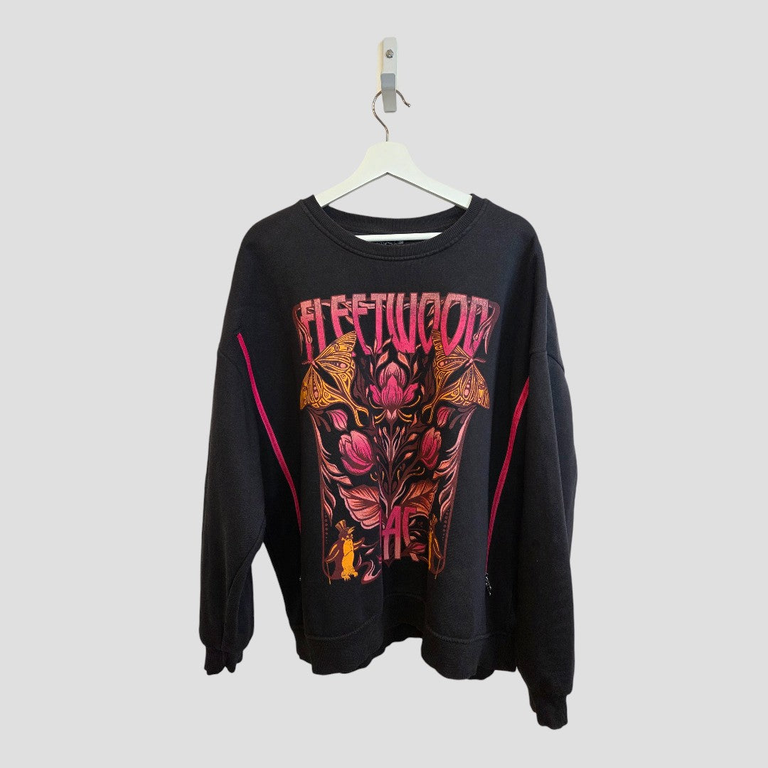 An affordable Primark black XL upcycled breastfeeding and pumping sweatshirt with colorful floral Fleetwood Mac graphic and bold "FLEETWOOD" print, displayed on a white hanger against a plain light background.
