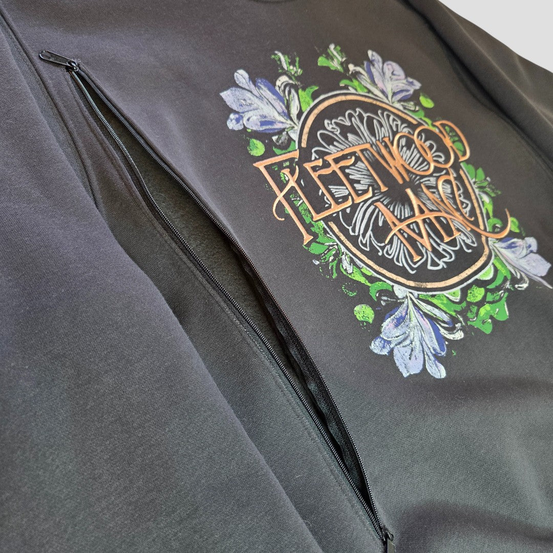 Close-up of a Primark Upcycled Breastfeeding & Pumping Embroidered Fleetwood Mac Band Sweatshirt (S): black, with floral graphics and a large diagonal zip pocket—an eco-friendly, affordable nursing and pumping option.