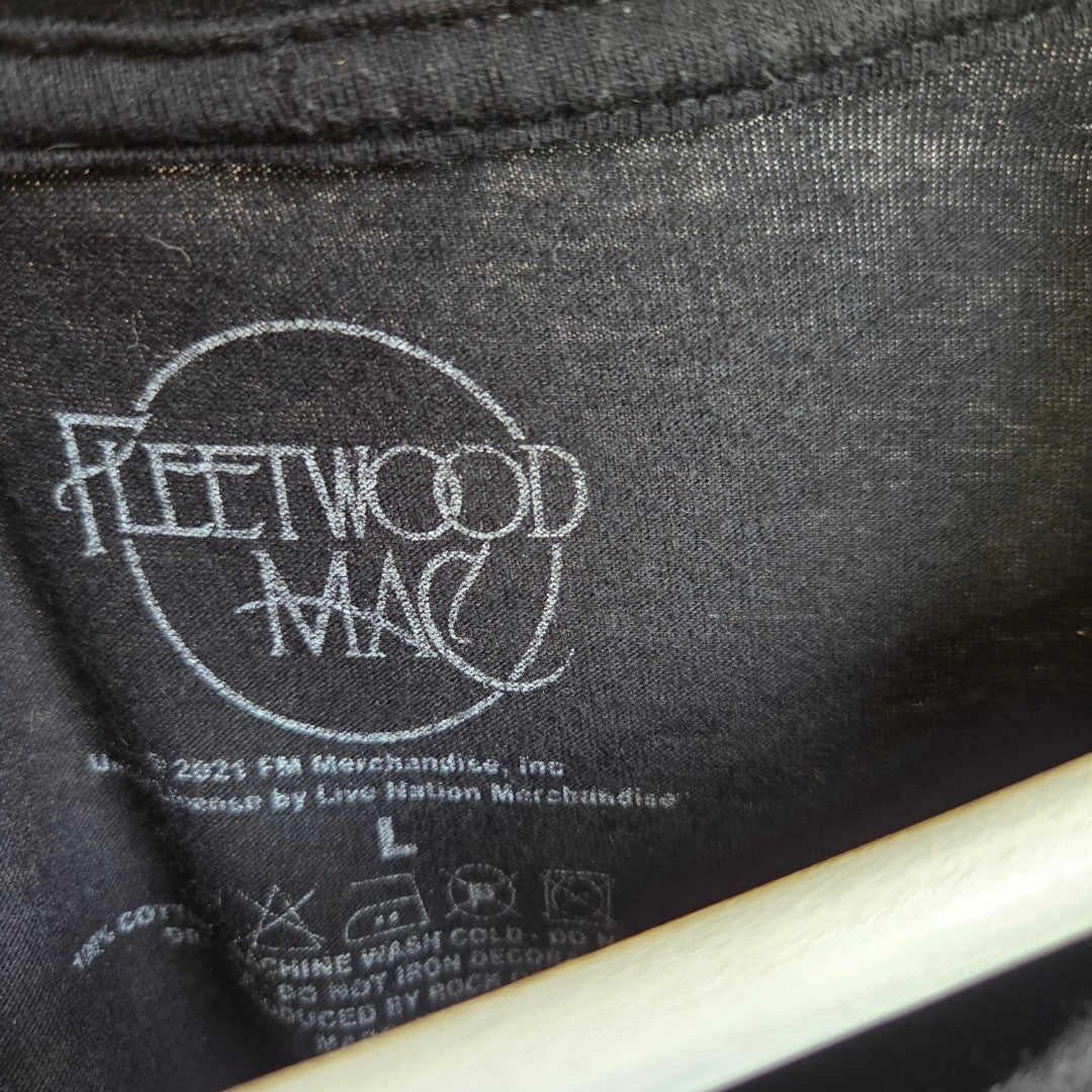 Black Fleetwood Mac Upcycled Nursing & Pumping Band T-Shirt (L, 100328) label features the Fleetwood Mac logo in white and eco-friendly care details, partly hidden by a hanger.
