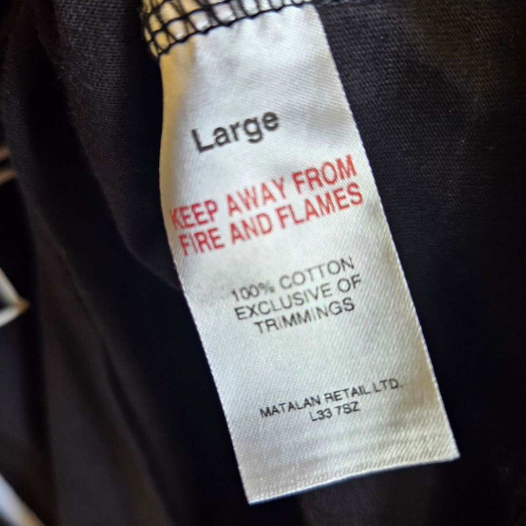 A white label on a black Upcycled Breastfeeding & Pumping Fleetwood Mac Band t-shirt (L) reads: Large. KEEP AWAY FROM FIRE AND FLAMES. 100% COTTON EXCLUSIVE OF TRIMMINGS—an eco-friendly choice by Fleetwood Mac.