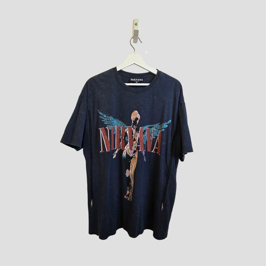A Primark Upcycled Breastfeeding & Pumping Nirvana Band t-shirt in grey/turquoise (M UK12/14) hangs on a white hanger against a light gray background, featuring the band's name and a winged anatomical figure. Stylish nursing wear for fans.
