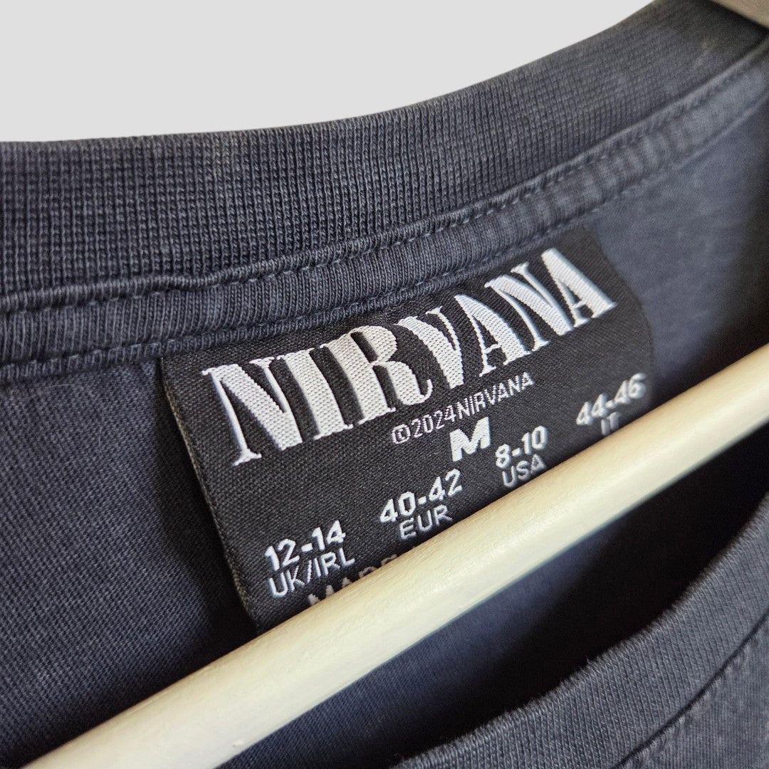 Close-up of a Primark Upcycled Breastfeeding & Pumping Nirvana Band t-shirt label (Grey/Turquoise, M UK12/14) on a wooden hanger—an affordable option ideal for pairing with nursing wear.