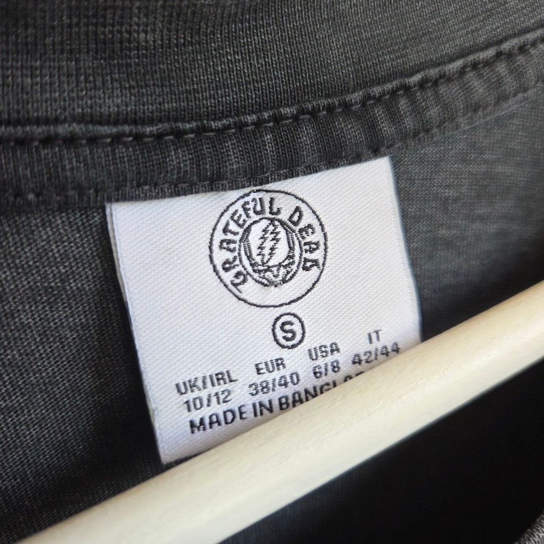 A close-up of the Primark tag on this upcycled Grateful Dead Band nursing & pumping T-shirt (Size S, UK10/12, Made in Bangladesh)—perfect for fans seeking comfortable and affordable breastfeeding wear.