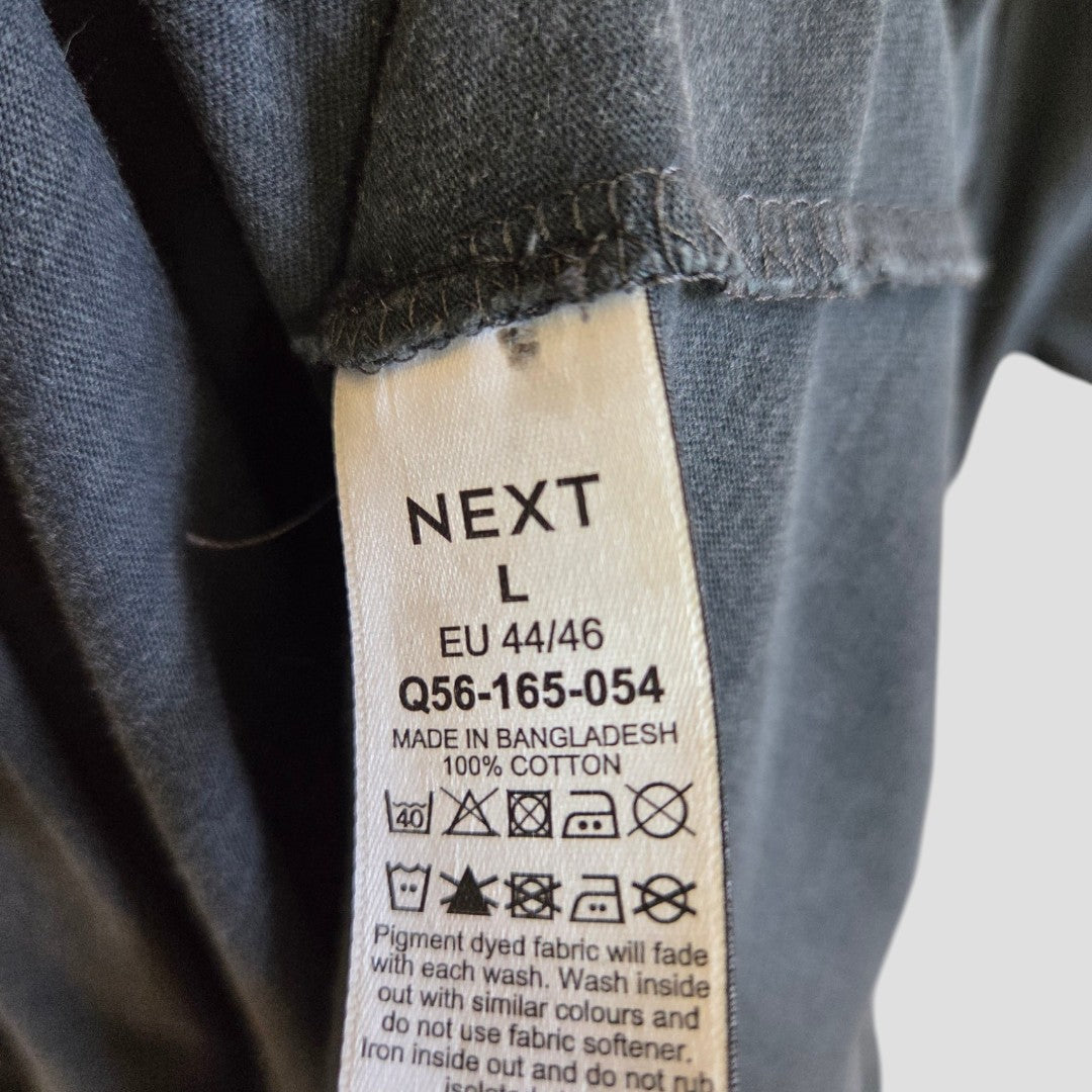 A close-up of the Next label on an upcycled grey Rolling Stones Floral Tongue Band breastfeeding & pumping t-shirt (L, 100334), made in Bangladesh from eco-friendly 100% cotton. Care symbols are visible, making it ideal for nursing comfort.