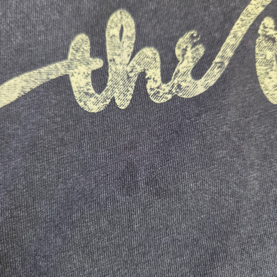 A close-up of eco-friendly, upcycled black Rolling Stones band tee fabric (Primark, UK12/14) with "the" in a light, distressed script—perfect for stylish breastfeeding and pumping dresses.