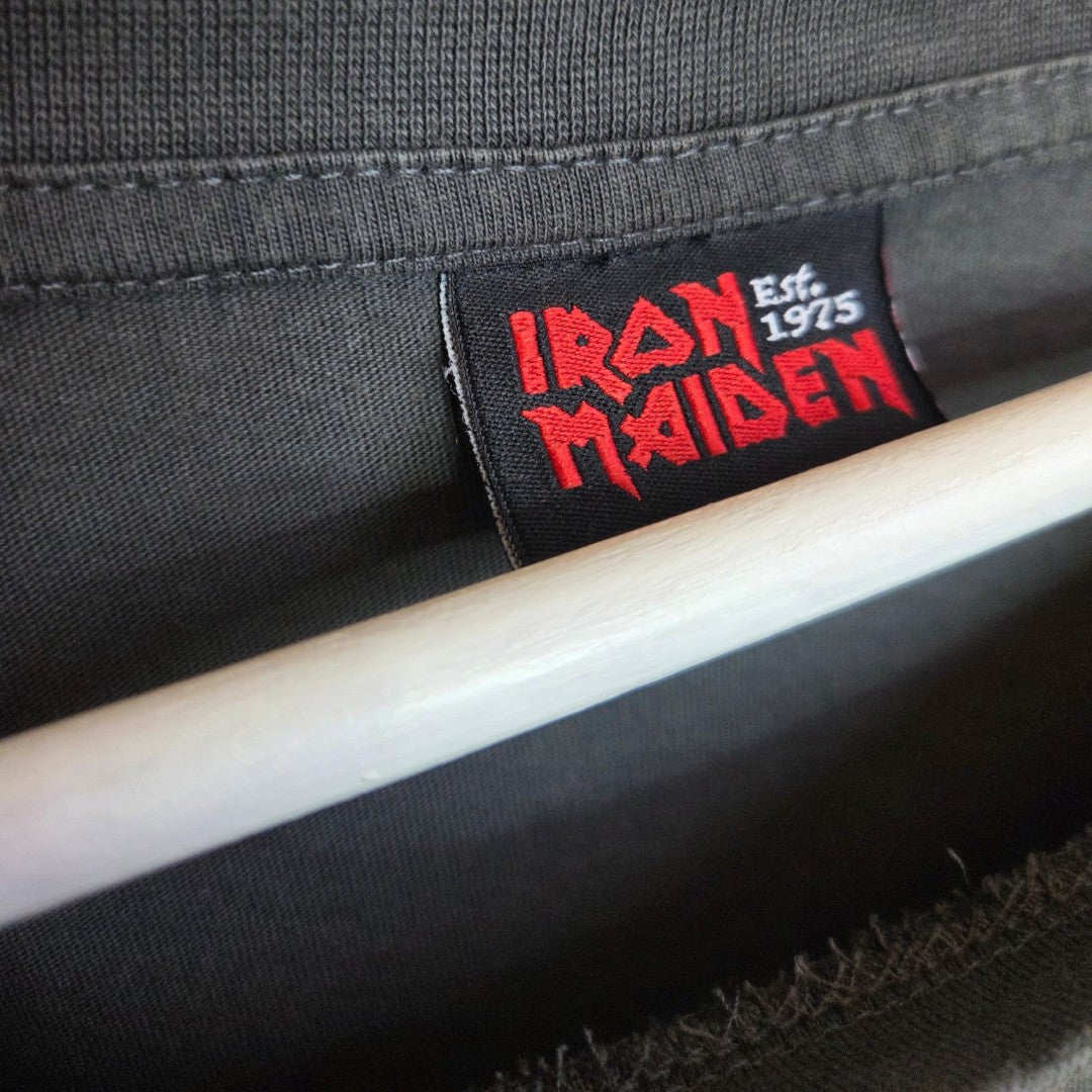 Close-up of a black label inside a George Upcycled Breastfeeding & Pumping Grey/Red Glitter Iron Maiden Band t-shirt UK20, showing the red Iron Maiden logo and Est. 1975 in white. A wooden hanger is partly visible below.
