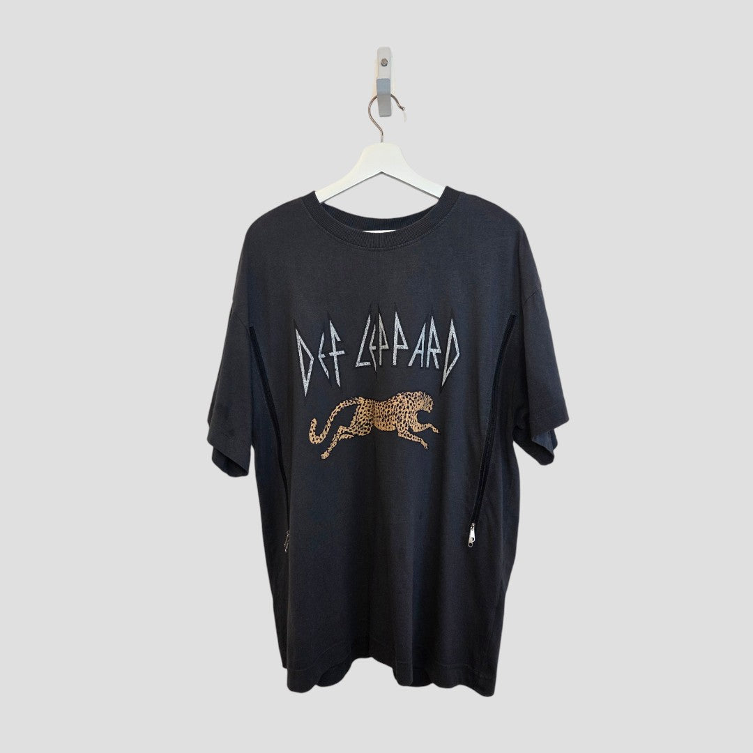 A grey upcycled H&M Def Leppard nursing & pumping t-shirt (L, 100384) featuring the band’s name and graphic, made from eco-friendly materials, is displayed on a white hanger against a plain gray background.