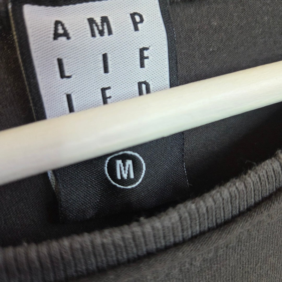 Close-up of a black AMPLIFIED label and size M tag on an upcycled eco-friendly nursing & pumping Metallica Guitar Band t-shirt (100381), hanging on a white hanger.