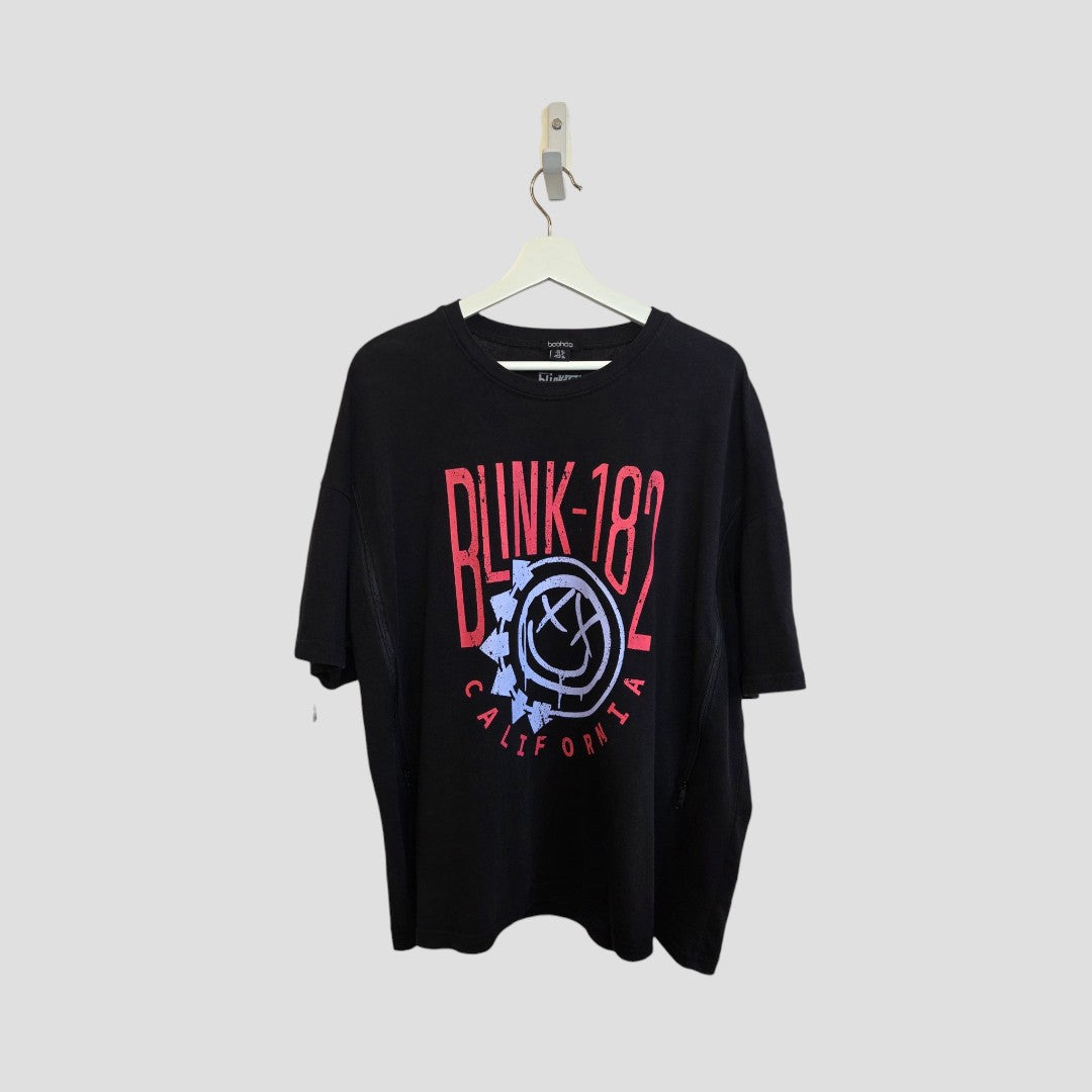 A black boohoo Upcycled Breastfeeding & Pumping Blink-182 Oversized Band T-shirt (UK12, 100413) hangs on a white hanger against a grey background, featuring bold red text and the band’s light blue and white smiley face logo.
