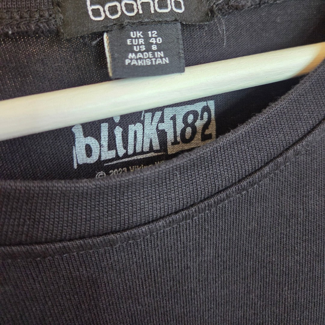 A close-up of the boohoo Upcycled Breastfeeding & Pumping Black Blink 182 Oversized Band t-shirt (UK12) on a hanger, featuring a blink-182 logo inside the collar and size tags—an eco-friendly choice for nursing. Made in Pakistan.