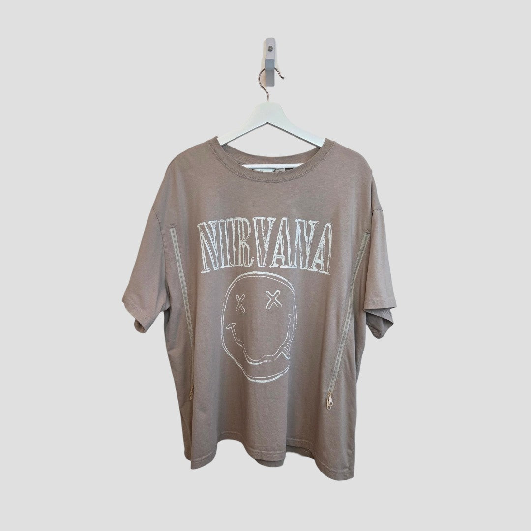 An upcycled H&M XXL beige Nirvana Smile Band T-shirt for breastfeeding and pumping, hanging on a white hanger against a plain background.