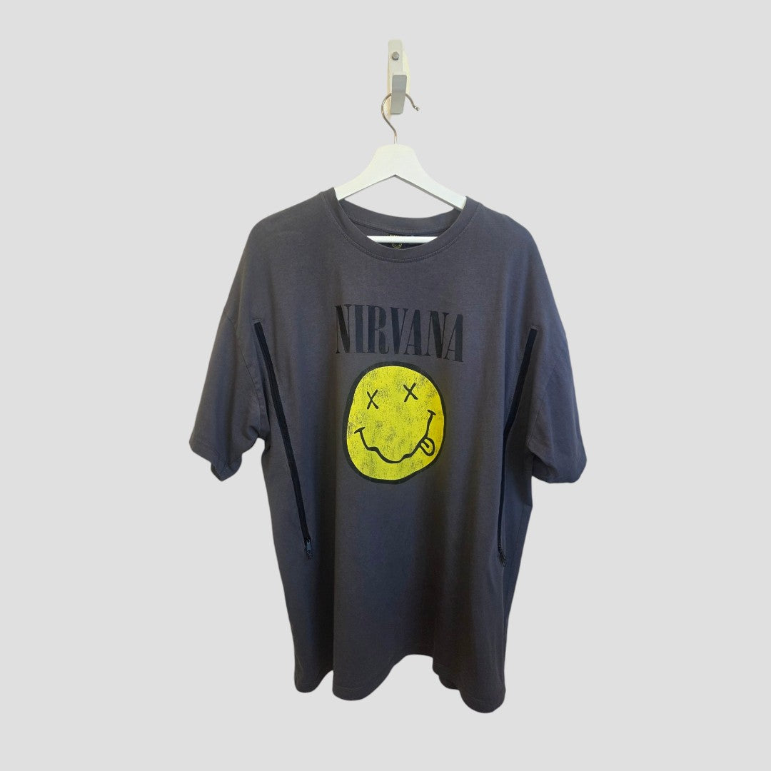 A dark gray upcycled Primark Nirvana XL t-shirt (UK18/20) hangs on a white hanger, featuring the band’s name and yellow smiley face graphic—made from eco-friendly materials for breastfeeding and pumping.