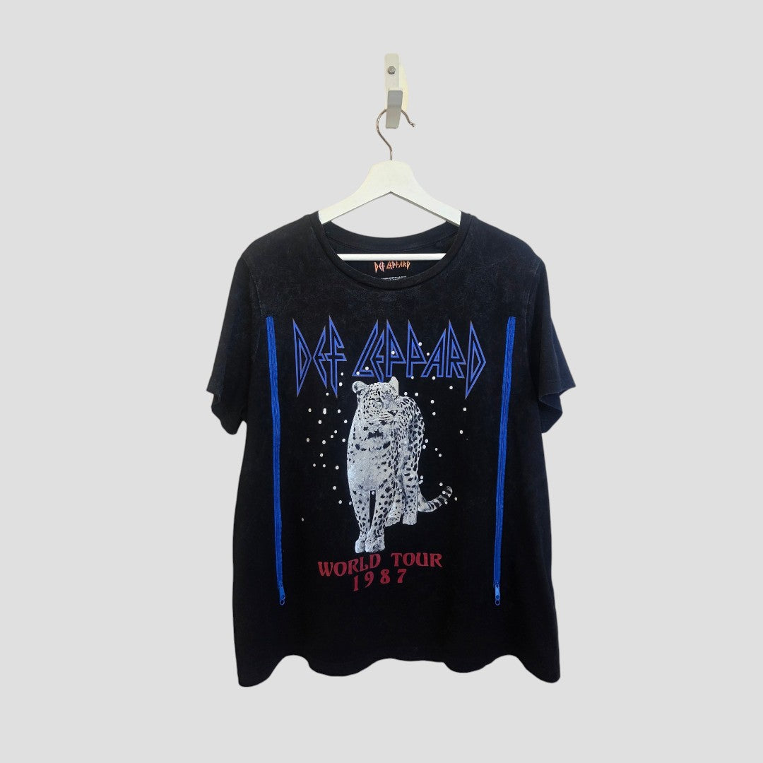 A black upcycled Def Leppard T-shirt (L) hangs on a hanger, featuring a leopard design, the band’s name in blue, and “World Tour 1987” in red—ideal affordable breastfeeding and pumping wear with rock 'n' roll style.
