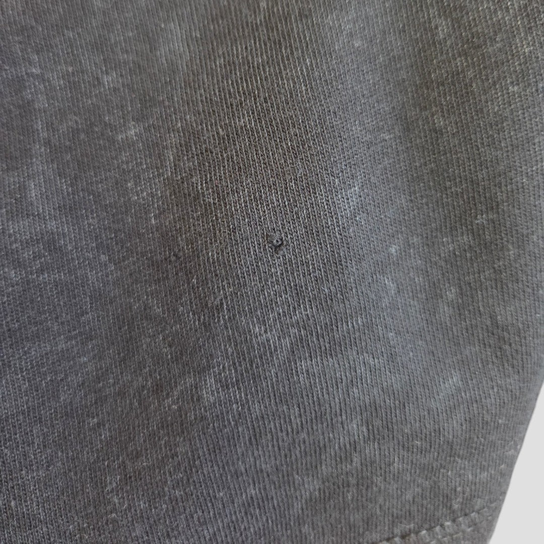Close-up of the Upcycled Breastfeeding & Pumping Black Snow Def Leppard Band t-shirt (L), showcasing dark grey fabric with a small center hole that highlights its fine texture and detailed stitching.