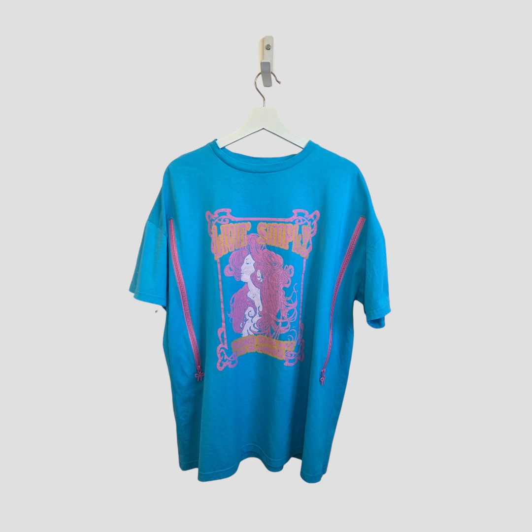 The Primark Upcycled Breastfeeding & Pumping Turquoise/Pink Girl Bow t-shirt (M, UK12/14) features pink side zippers, a large graphic of a stylized woman with flowing hair and back text, shown on a white hanger against a light background.