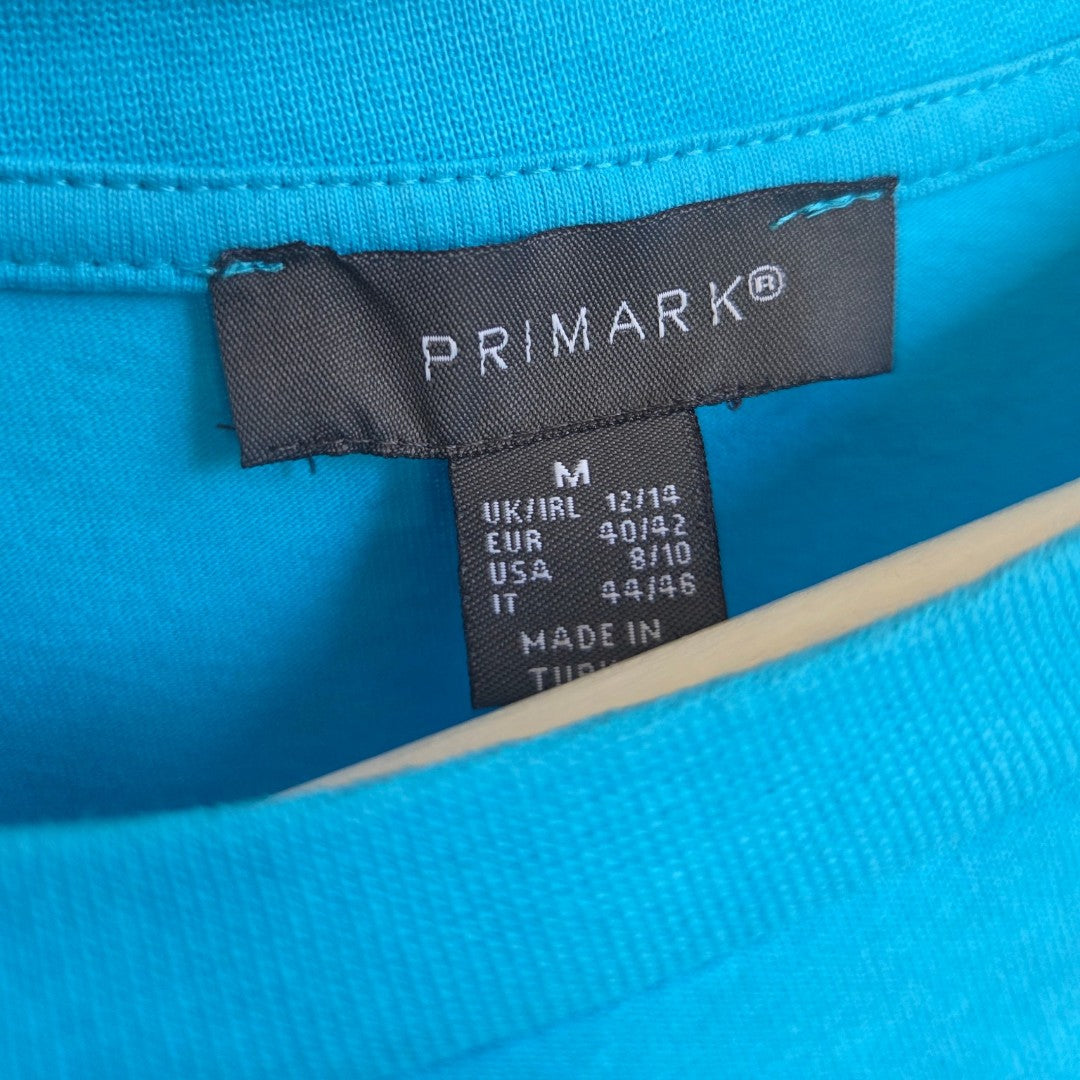 Close-up of a Primark Upcycled Breastfeeding & Pumping Turquoise/Pink Girl Bow t-shirt (M, UK12/14) label, made in Turkey—an affordable and stylish choice for nursing mothers.