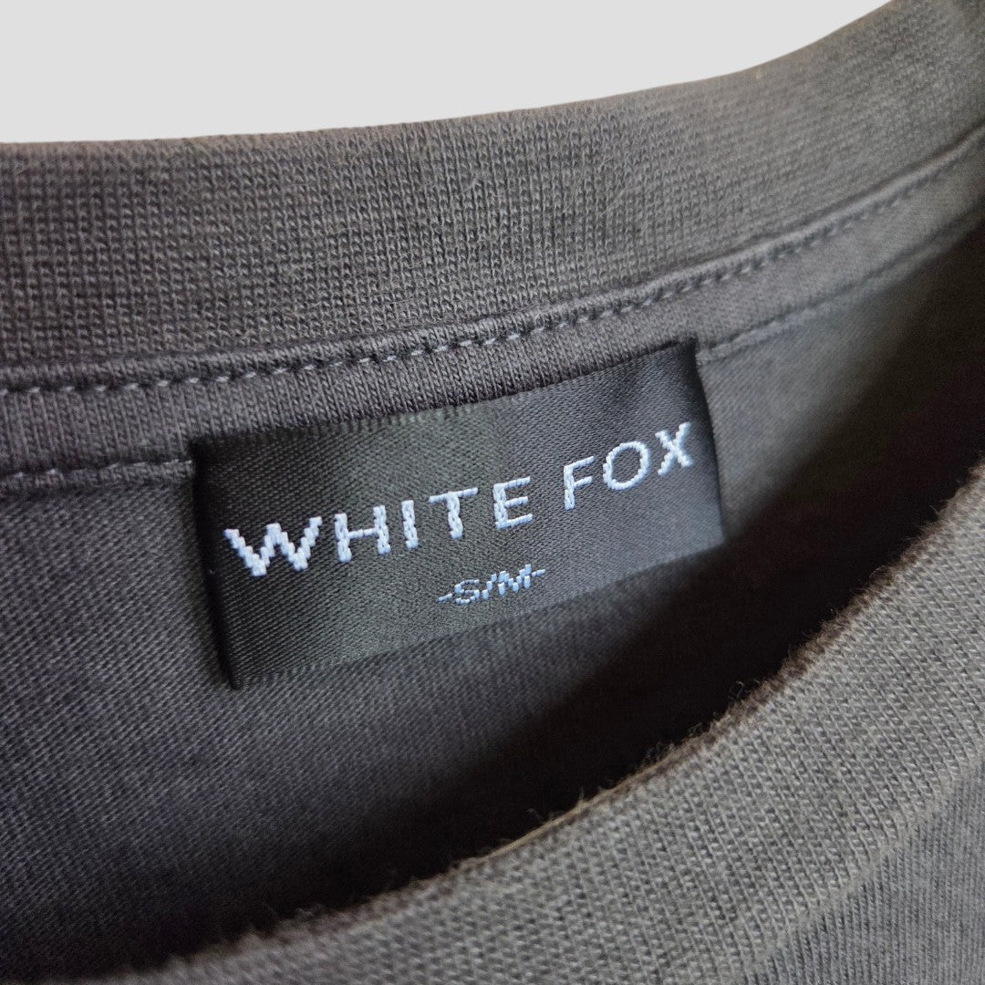 Close-up of a black label stitched inside a dark gray Upcycled Breastfeeding & Pumping Grey/Red White Fox t-shirt (S/M), showing the WHITE FOX brand and size.