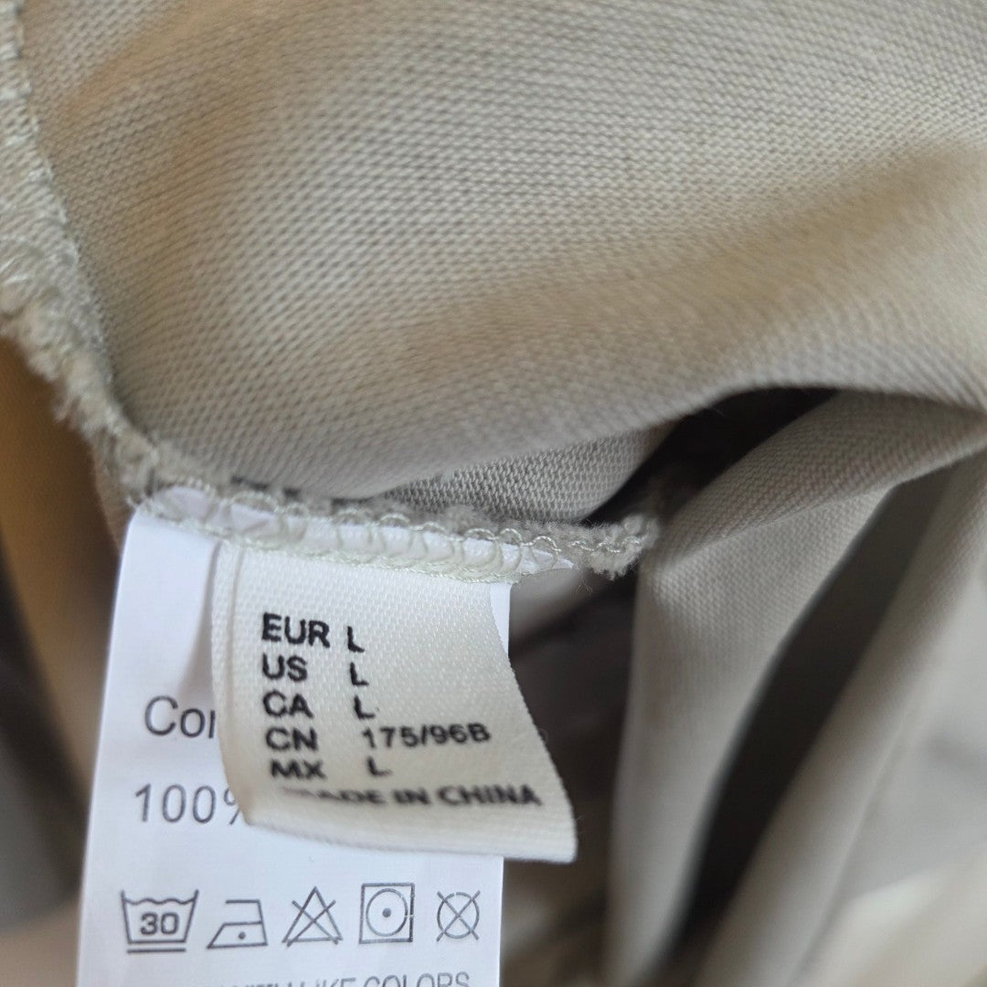 A close-up of the White Fox Upcycled Breastfeeding & Pumping Khaki/White t-shirt label shows size L, 100% cotton, made in China—ideal for those seeking comfortable, affordable nursing wear.
