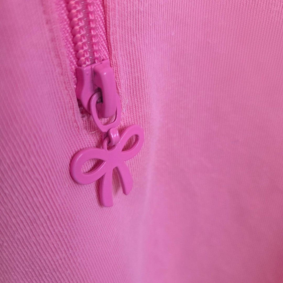 Close-up of a bow-shaped zipper pull on the Upcycled Breastfeeding & Pumping Pink Colourful Retro Adidas t-shirt (size L), featuring pink fabric and easy nursing access.