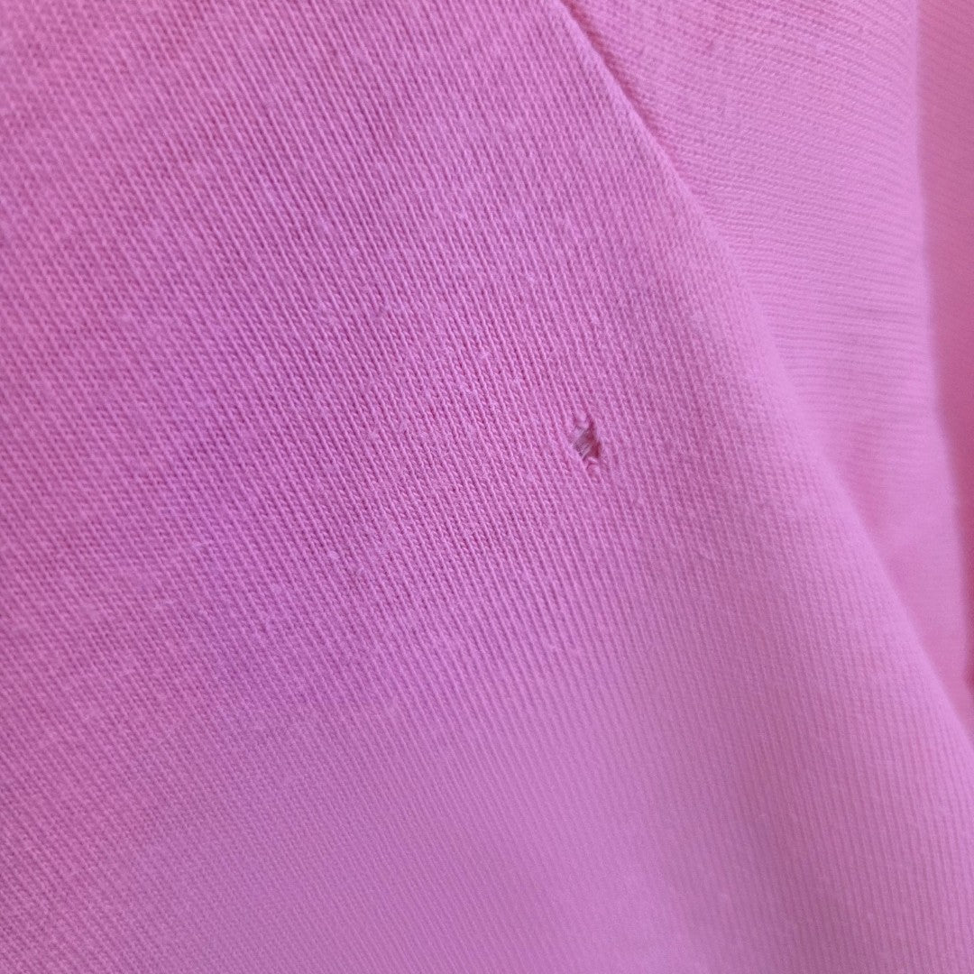 Close-up of pink Upcycled Breastfeeding & Pumping Retro Adidas t-shirt (L) featuring bow zips, showing a small hole with slight fraying near the center.