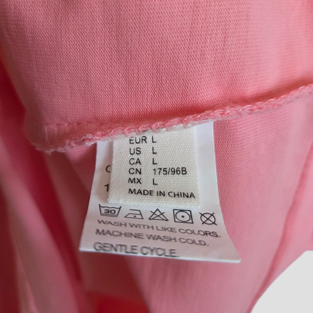 A close-up of the White Fox Upcycled Breastfeeding & Pumping Pink/Red t-shirt (size L, 100497) shows its care label with international sizing, washing instructions, and "Made in China" printed on the tag.