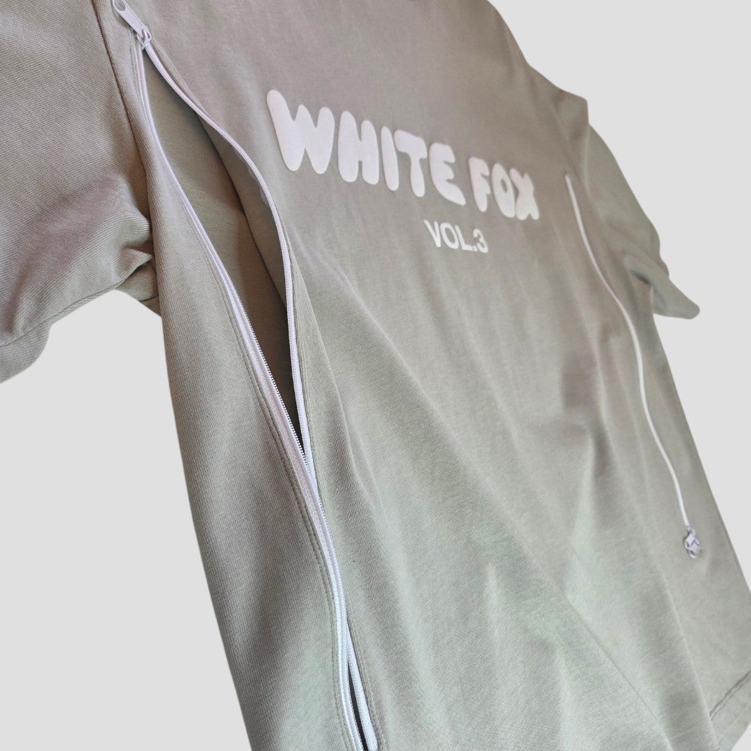 The White Fox Upcycled Breastfeeding & Pumping Khaki/White t-shirt (L) features white zippers and "WHITE FOX VOL.3" printed across the chest, shown laid flat on a light gray background.