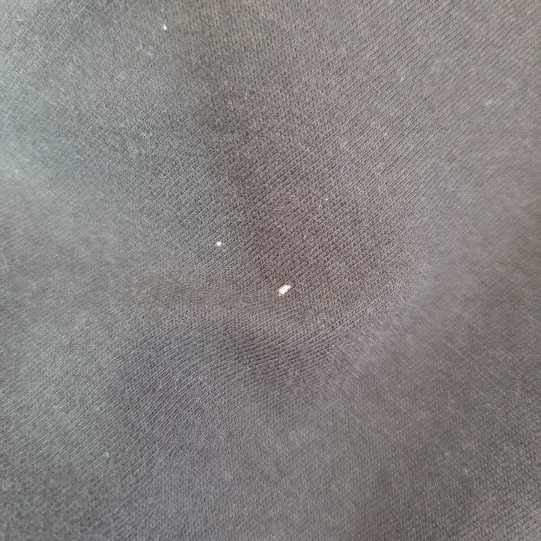 Close-up of eco-friendly, affordable dark fabric from the Amplified Upcycled Breastfeeding & Pumping Grey AC/DC Highway Band t-shirt XL (100485), showing visible lint and small white specks on the textured weave.