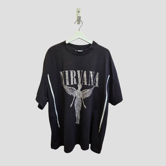 Upcycled H&M grey/cream Nirvana Angel Band t-shirt (XL) for breastfeeding & pumping, with NIRVANA lettering and angel graphic on the front, shown hanging on a white hanger against a plain gray background.