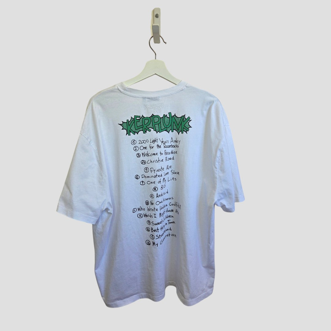 An upcycled ASOS breastfeeding and pumping White Green Day Band t-shirt (XL, 100493) hangs on a hanger, featuring green graffiti-style KEPPRUNK text and a handwritten tracklist on the back, displayed against a plain light background.