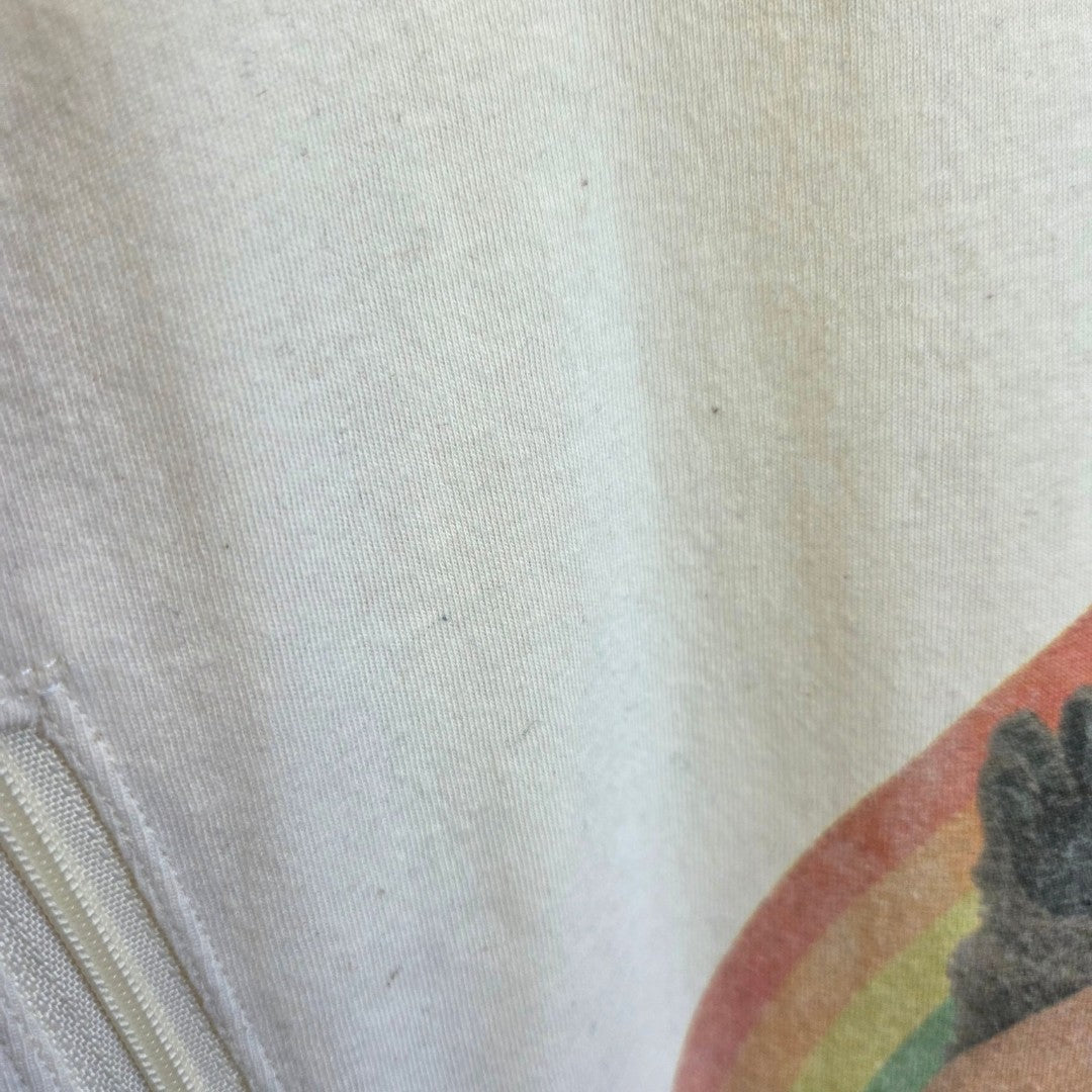Close-up of a white Truffle Shuffle Upcycled Breastfeeding & Pumping Rainbow Kids TV t-shirt (L), showing part of a colorful rainbow graphic and the edge of a zipper on the left side.