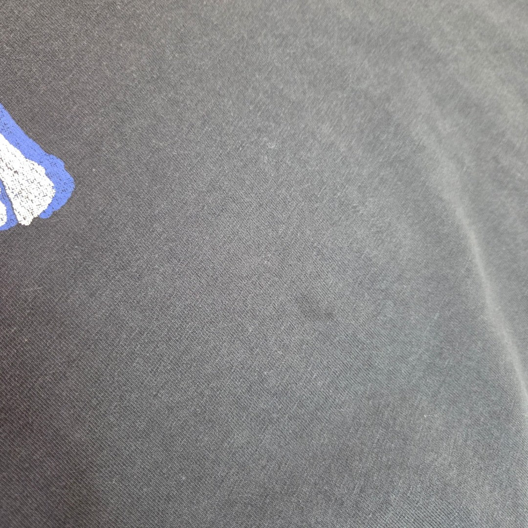 A close-up of the H&M Upcycled Breastfeeding & Pumping Grey/Pink Nirvana Angel Band t-shirt (L, 100509) shows the fabric’s texture and a glimpse of blue and white print in the upper left corner.