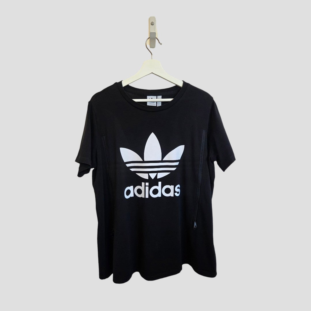 Upcycled Adidas XXL black/white logo T-shirt (UK24/26) for breastfeeding & pumping, hanging on a wooden hanger against a plain light gray background. Comfortable option for casual nursing wear.