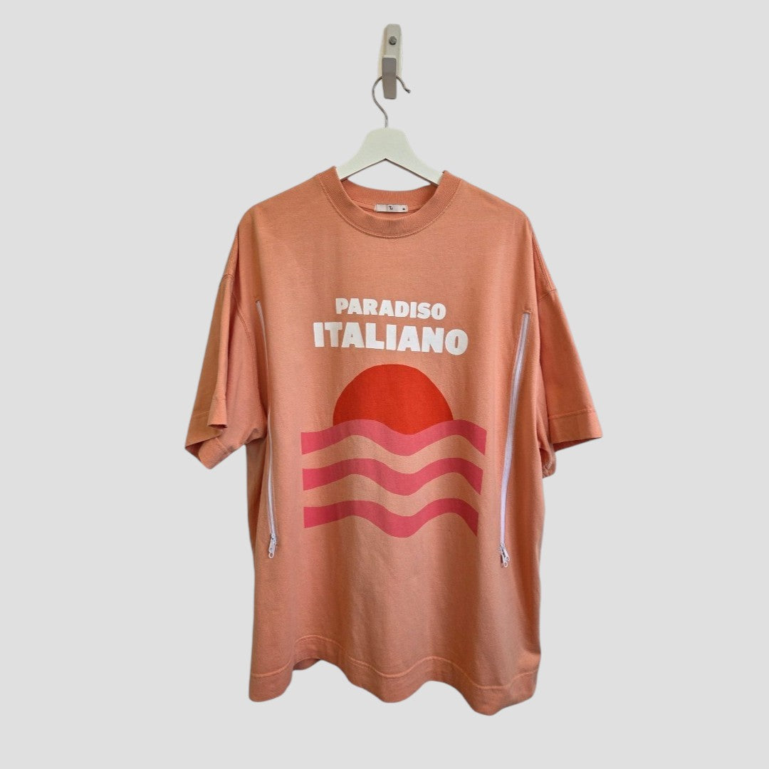 The Tu Upcycled Breastfeeding & Pumping Coral Paradiso Italiano T-shirt XL features a peach color, PARADISO ITALIANO text above a red sun with wavy stripes, and white side zippers for practical nursing or pumping.