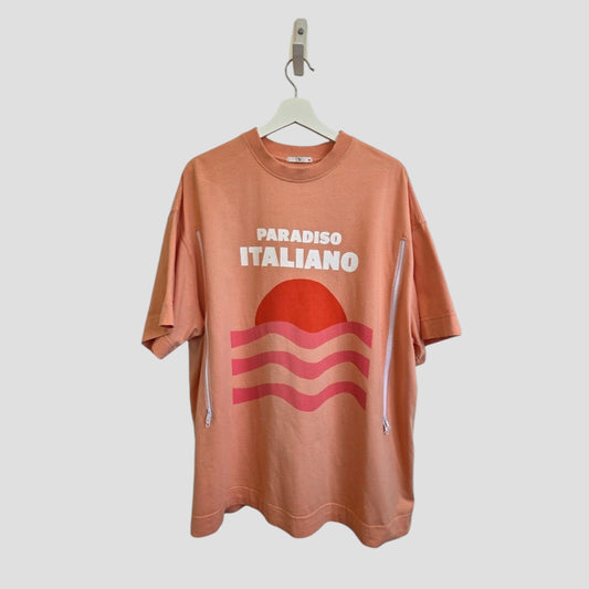 The Tu Upcycled Breastfeeding & Pumping Coral Paradiso Italiano T-shirt XL features a peach color, PARADISO ITALIANO text above a red sun with wavy stripes, and white side zippers for practical nursing or pumping.