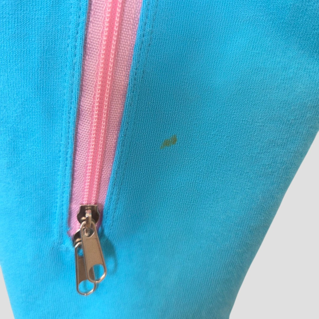 Close-up of Primark Upcycled Breastfeeding & Pumping Turquoise/Pink Girl t-shirt L (UK14/16) shows light blue fabric with a pink zipper and two silver pulls; a small, faint yellowish stain is visible near the zipper.