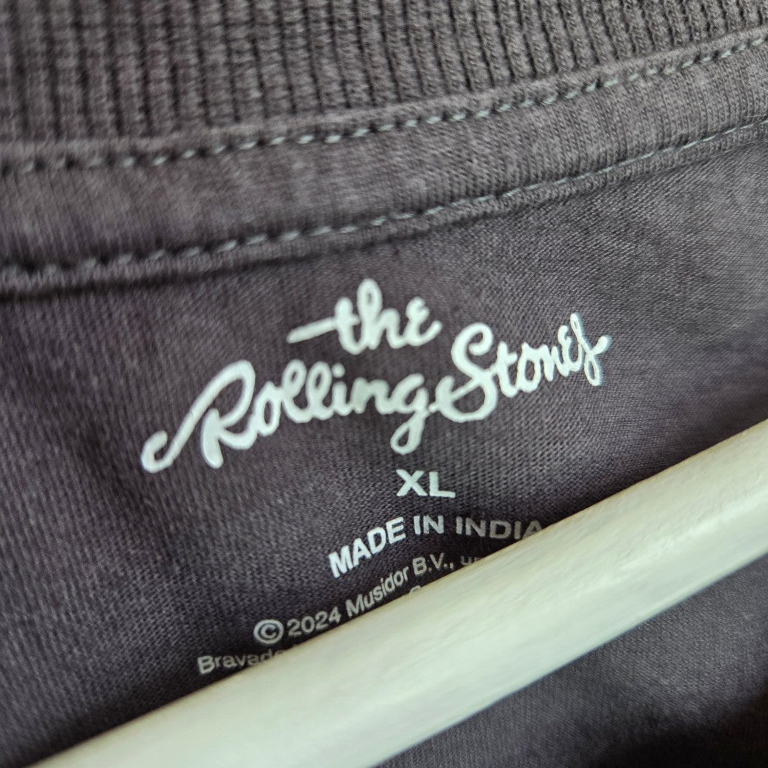 Close-up of a black Primark tag on an upcycled grey/red The Rolling Stones Tongue Band breastfeeding & pumping t-shirt, size XL. Some text is visible, and part of a hanger appears at the bottom.