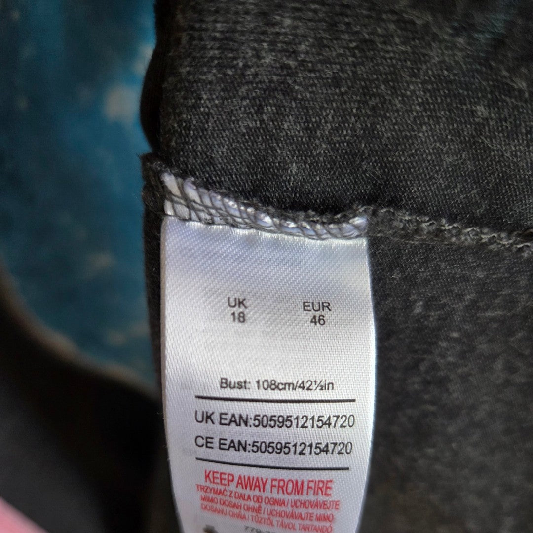 A close-up of the Universal Upcycled Breastfeeding & Pumping Grey E.T. t-shirt UK18 label shows size UK18/EUR46, bust 108cm/42.4in, eco-friendly materials, and care instructions including 'keep away from fire'.