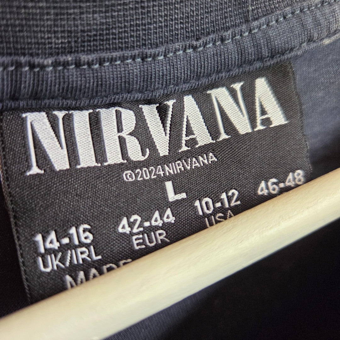 Close-up of a Primark label on an Upcycled Breastfeeding & Pumping Grey/Turquoise Nirvana Angel Band t-shirt (L, UK14/16; 100469). The shirt hangs on a wooden hanger—perfect for showcasing affordable nursing clothing.