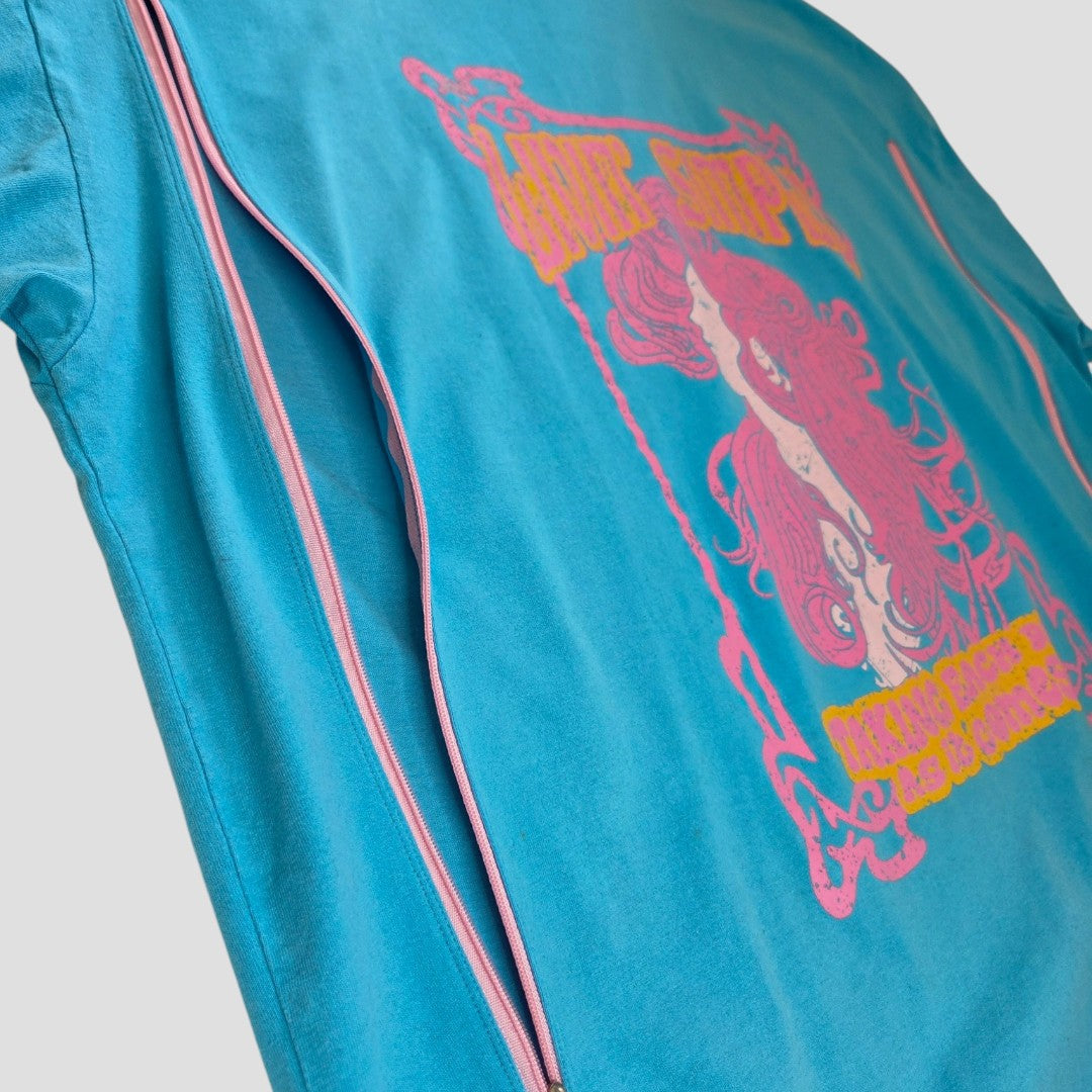 A close-up of Primark's Upcycled Breastfeeding & Pumping Turquoise/Pink Girl t-shirt (L, UK14/16) shows a woman graphic with pink/yellow accents and stylized text, plus a side pink zipper for easy nursing.