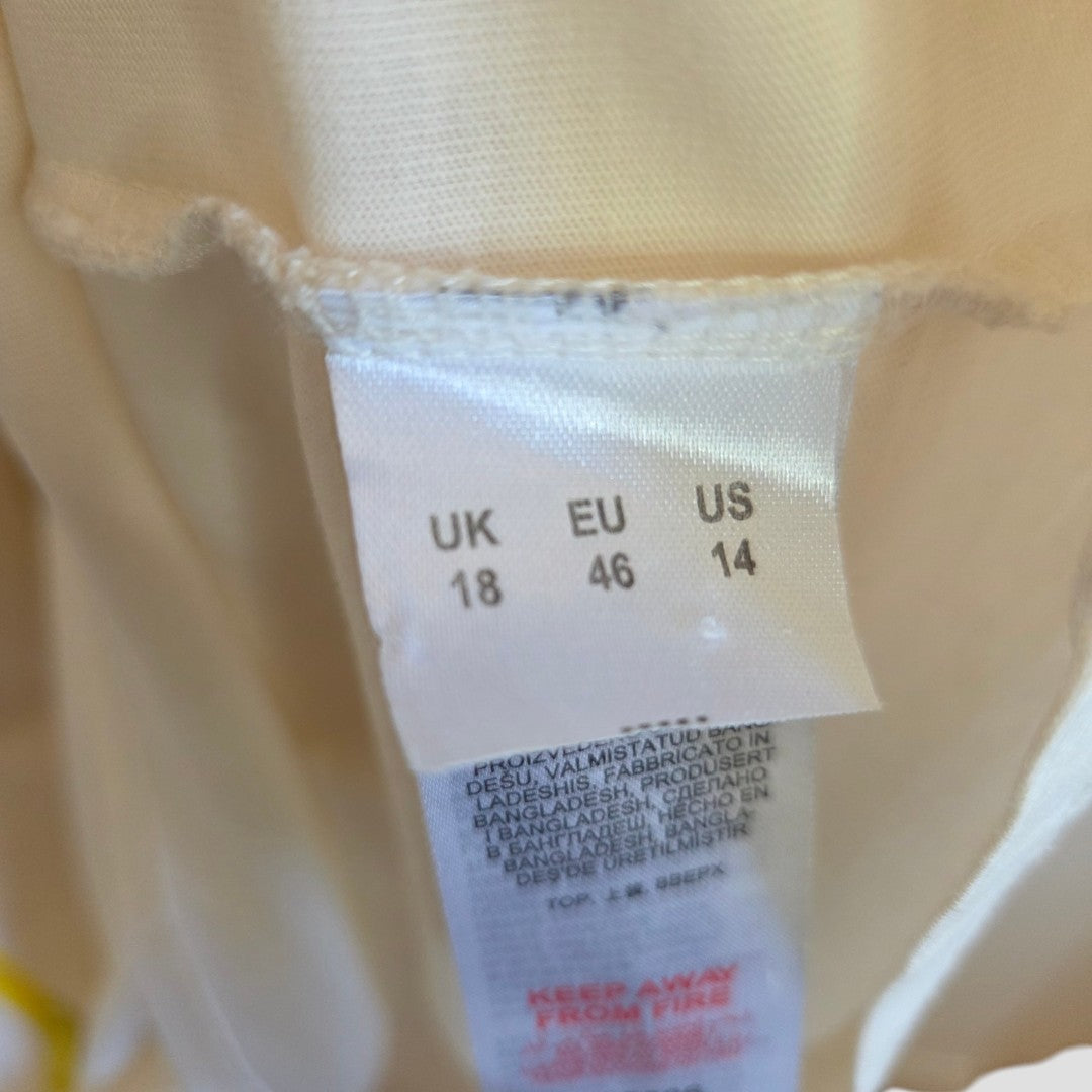 A close-up of the Simply Be Upcycled Breastfeeding & Pumping Cream Limon Lemon t-shirt label (UK18, EU46, US14), with care instructions in several languages on light beige fabric.