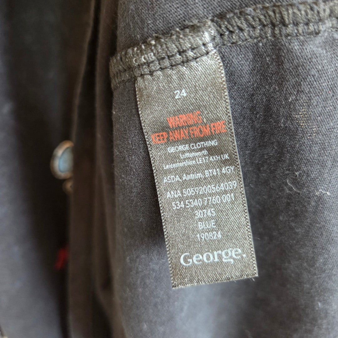 A close-up of a label on dark fabric shows size UK24, a fire safety warning in red, the George brand, care instructions, and details for the Upcycled Breastfeeding & Pumping Black The Rolling Stones Stars Band t-shirt (100571).